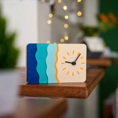 Colorful clock with wavy design on a wooden surface, blurred indoor background
