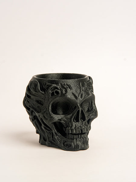 Black skull-shaped candle holder on a light beige background
