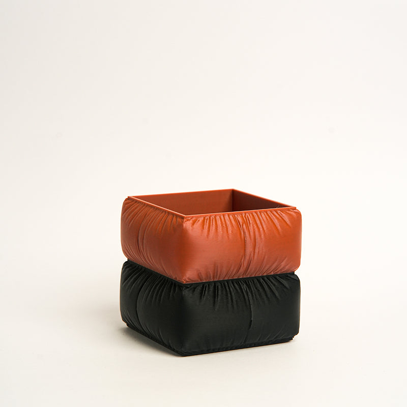Two stacked fabric containers, one orange and one black, on a white background