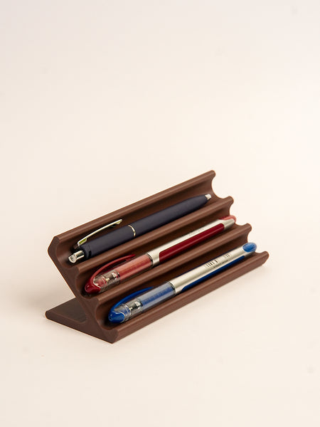 Wooden pen holder with three pens on a beige background