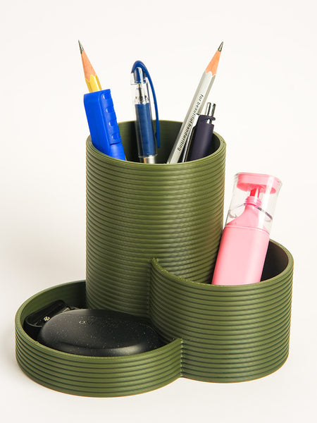 Green multi-compartment desk organizer with stationery items on a white background