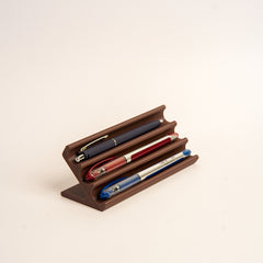 Wooden pen holder with three pens on a  white background