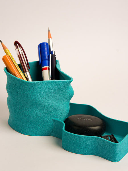 Teal pen holder with stationery items on a light background