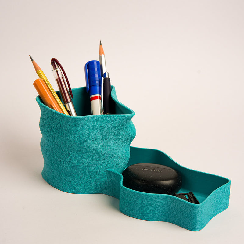 Teal pen holder with stationery items on a light background