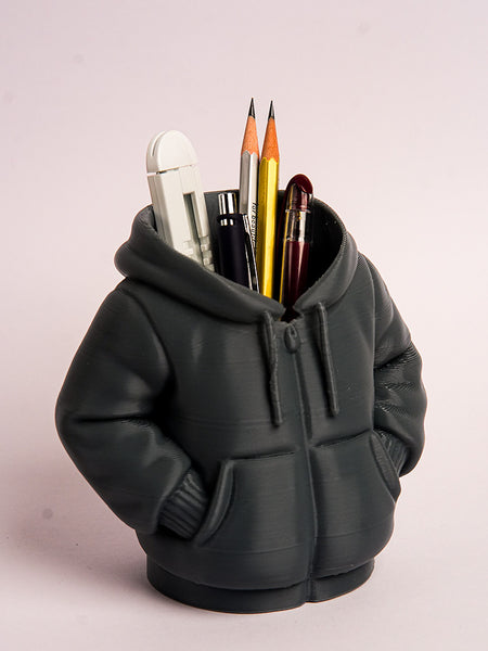 Black hoodie-shaped pen holder with stationery items on a light pink background