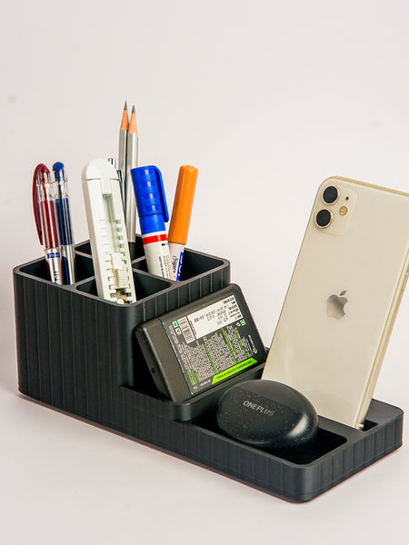 Black desk organizer with stationery items and a phone on a light gray background