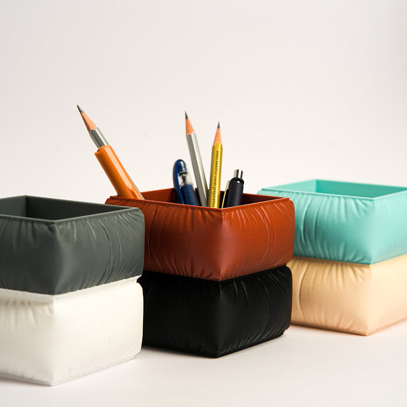 Colorful geometric pencil holders with pens on a white background