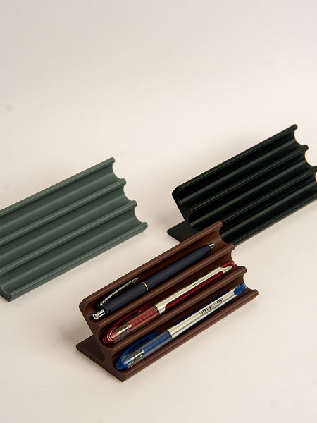 Three pen holders in different colors on a light background