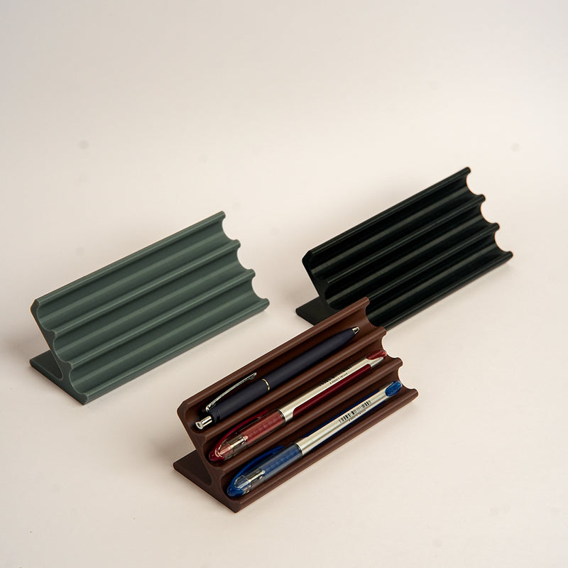 Three pen holders in different colors on a light background