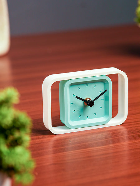 Teal clock with white frame on a wooden surface