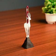 Deer-shaped pen holder with a red pen on a wooden surface