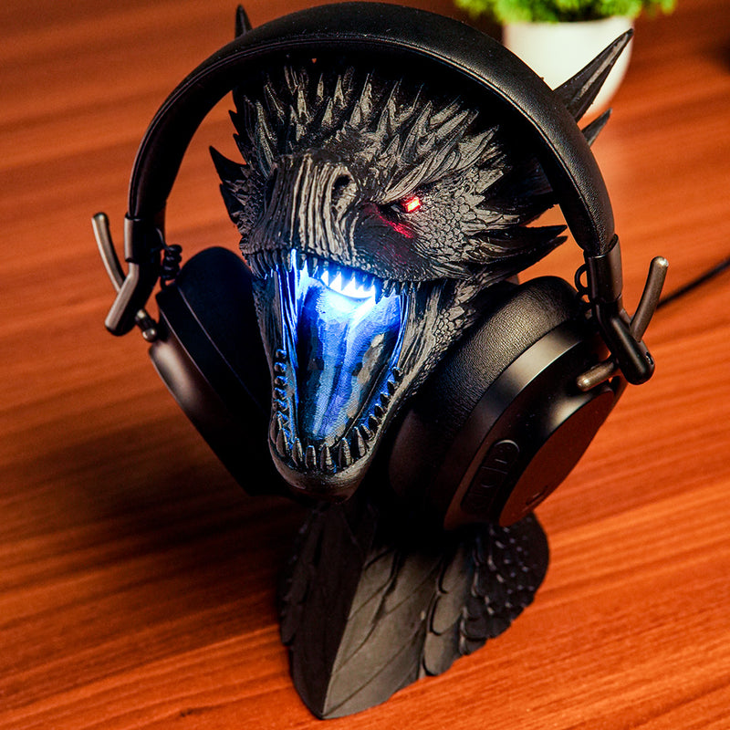Dragon-themed gaming headset with glowing blue mouth on a wooden surface