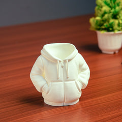 White hoodie-shaped night light on a wooden surface with a blurred plant in the background