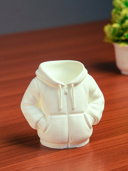 White hoodie-shaped night light on a wooden surface with a blurred plant in the background