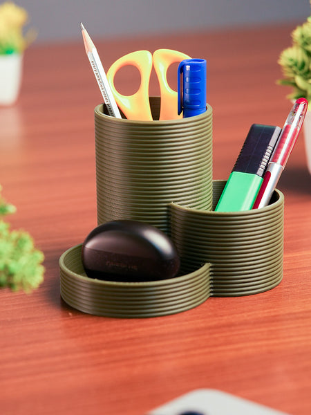 Green cylindrical desk organizer with stationery items on a wooden surface