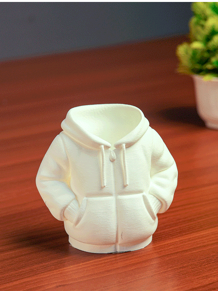 Black hoodie-shaped pen holder with stationery items on a light pink background