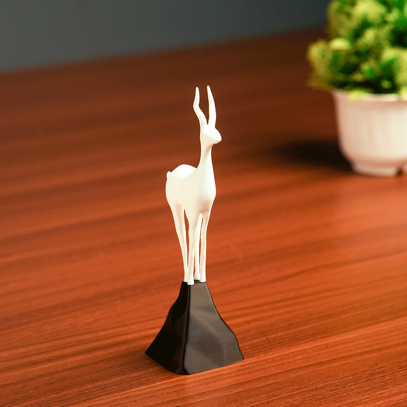 White deer figurine on a black stand against a beige background